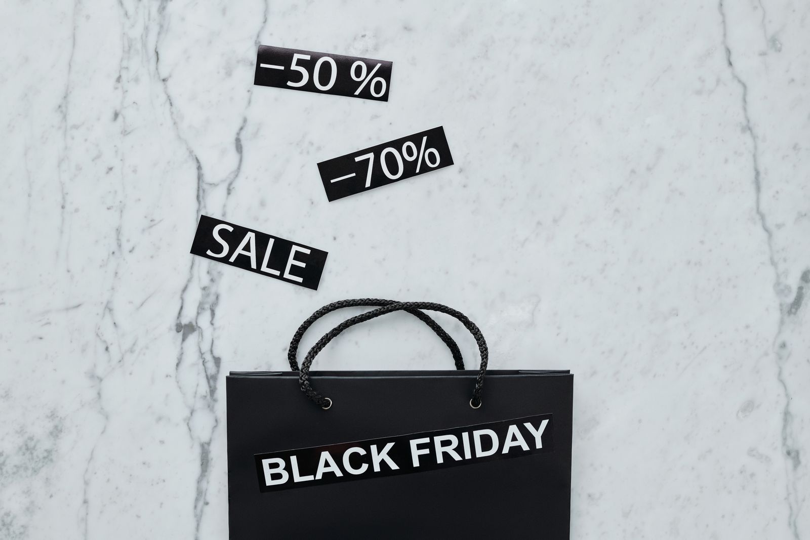 Butikkvindu med store røde Black Friday-salgsplakater og kunder med handleposer